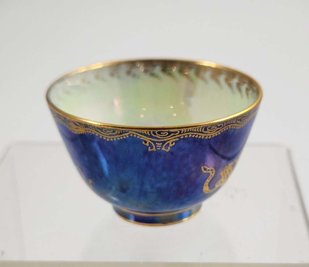 A miniature Wedgwood lustre porcelain cup featuring a cobalt blue iridescent exterior decorated with gilded dragon motifs and a pale iridescent green interior. View II