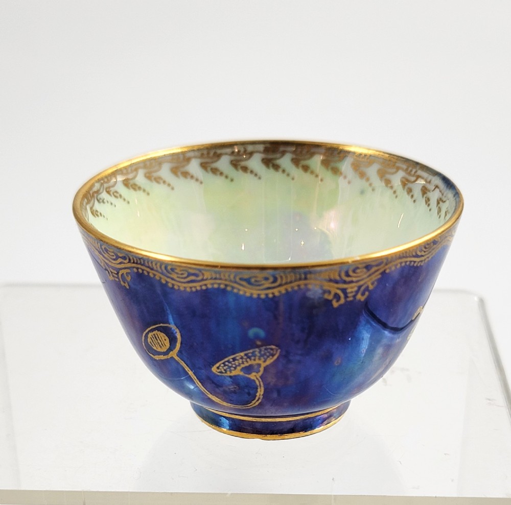 A miniature Wedgwood lustre porcelain cup featuring a cobalt blue iridescent exterior decorated with gilded dragon motifs and a pale iridescent green interior. View V