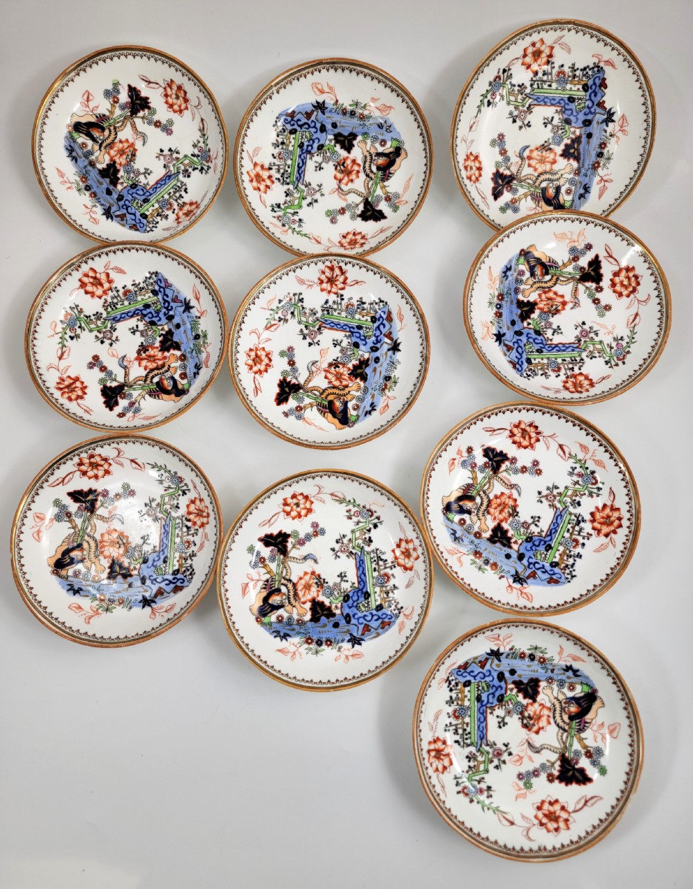 A Victorian Minton porcelain tea set featuring cups, stacked saucers, and a milk jug adorned with polychrome Kakiemon style tigers, bamboo, and flora. View III