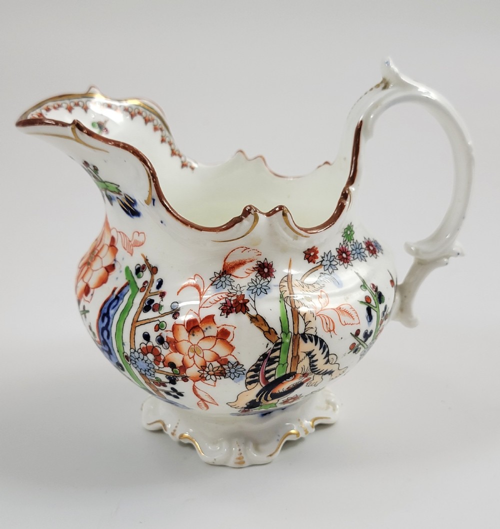 A Victorian Minton porcelain tea set featuring cups, stacked saucers, and a milk jug adorned with polychrome Kakiemon style tigers, bamboo, and flora. View VI
