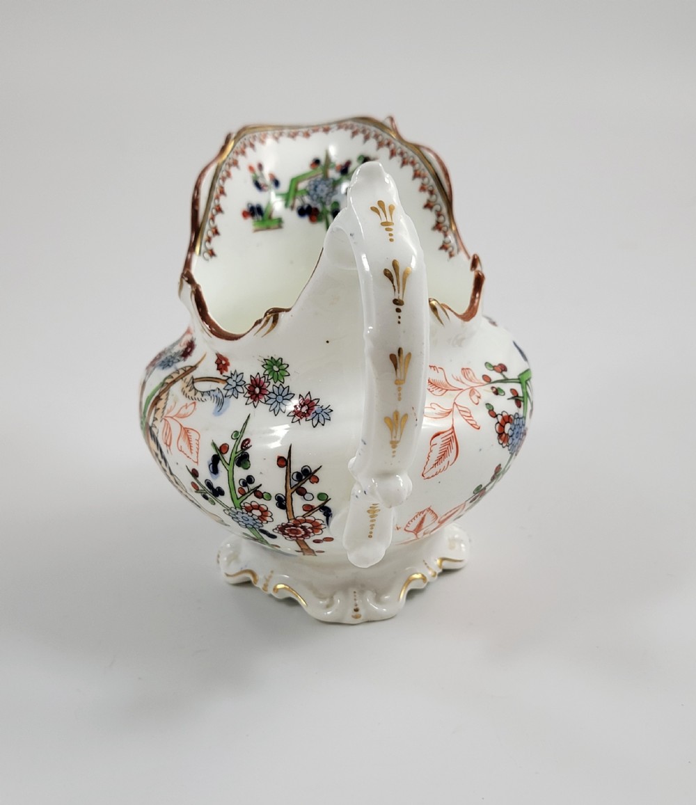 A Victorian Minton porcelain tea set featuring cups, stacked saucers, and a milk jug adorned with polychrome Kakiemon style tigers, bamboo, and flora. View IX
