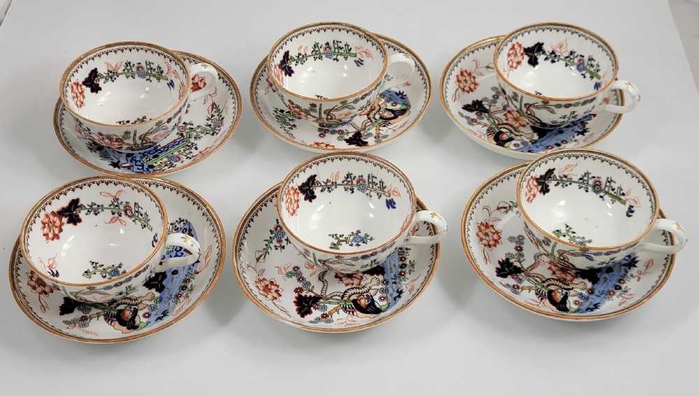 A Victorian Minton porcelain tea set featuring cups, stacked saucers, and a milk jug adorned with polychrome Kakiemon style tigers, bamboo, and flora. View XIV