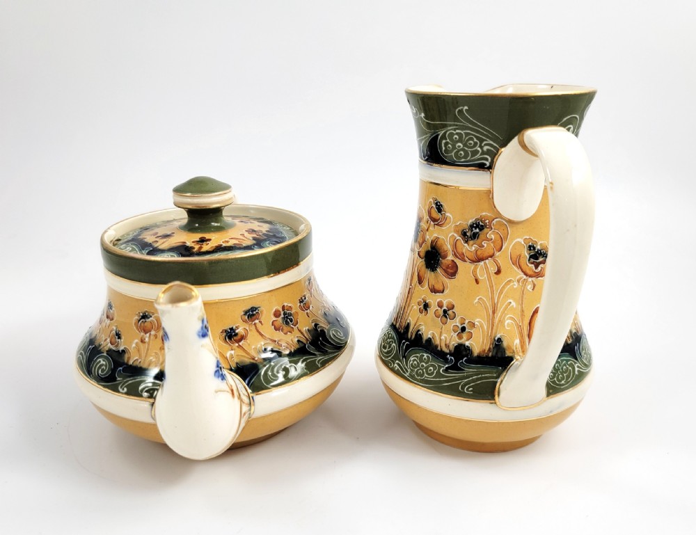 An antique four-piece Art Nouveau ceramic tea service decorated with tube-lined ochre poppy motifs and dark green glaze borders with gilded accents. View II
