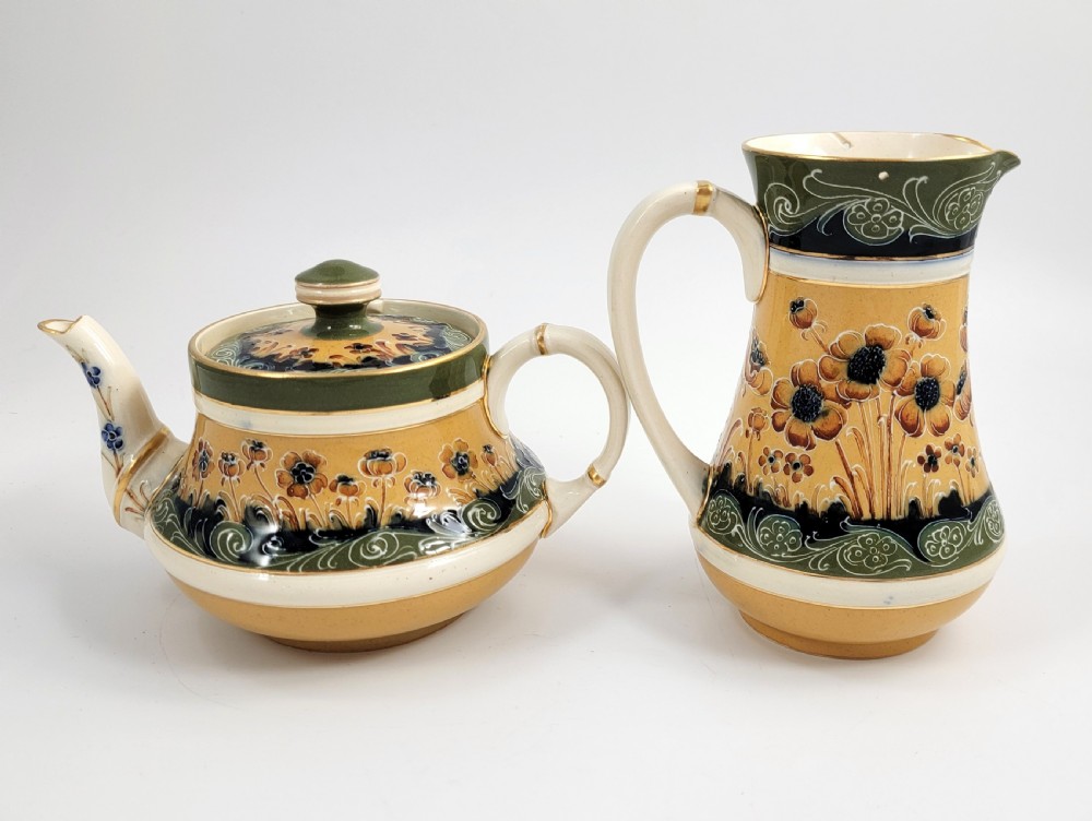 An antique four-piece Art Nouveau ceramic tea service decorated with tube-lined ochre poppy motifs and dark green glaze borders with gilded accents. View III