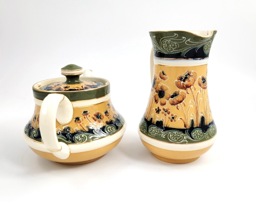 An antique four-piece Art Nouveau ceramic tea service decorated with tube-lined ochre poppy motifs and dark green glaze borders with gilded accents. View IV