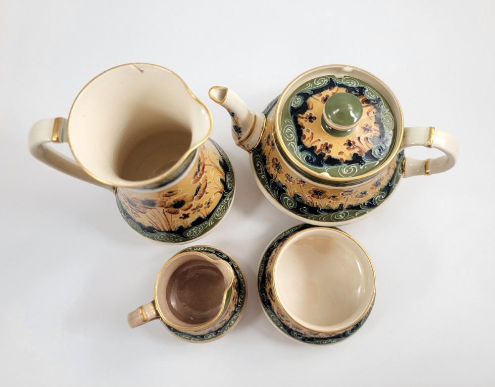 An antique four-piece Art Nouveau ceramic tea service decorated with tube-lined ochre poppy motifs and dark green glaze borders with gilded accents. View IX