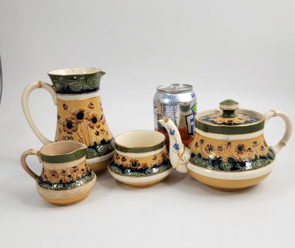 An antique four-piece Art Nouveau ceramic tea service decorated with tube-lined ochre poppy motifs and dark green glaze borders with gilded accents. View XIII
