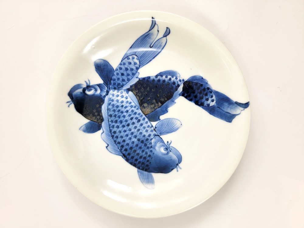 A near-pair of circular white Japanese porcelain plates decorated with hand-painted cobalt blue depictions of two koi fish. View IV