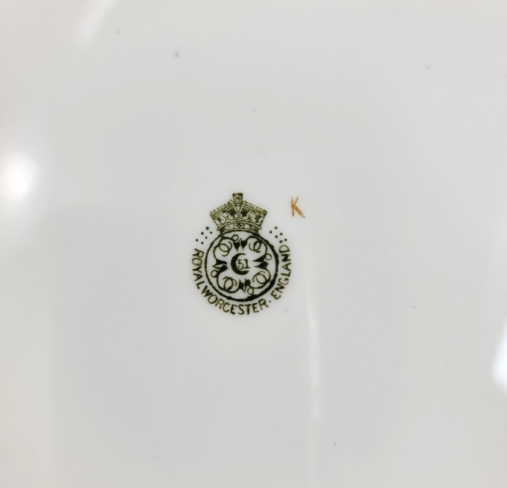 An Edwardian Royal Worcester circular porcelain cabinet plate with a cobalt blue rim decorated in heavy tooled gilding and six small floral cartouches surrounding a central hand-painted bouquet. View IV
