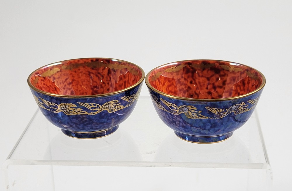 A pair of small Wedgwood lustre porcelain bowls featuring a cobalt blue exterior decorated with gilt birds and a mottled orange interior. View II
