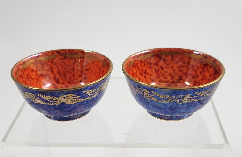 A pair of small Wedgwood lustre porcelain bowls featuring a cobalt blue exterior decorated with gilt birds and a mottled orange interior. View VI