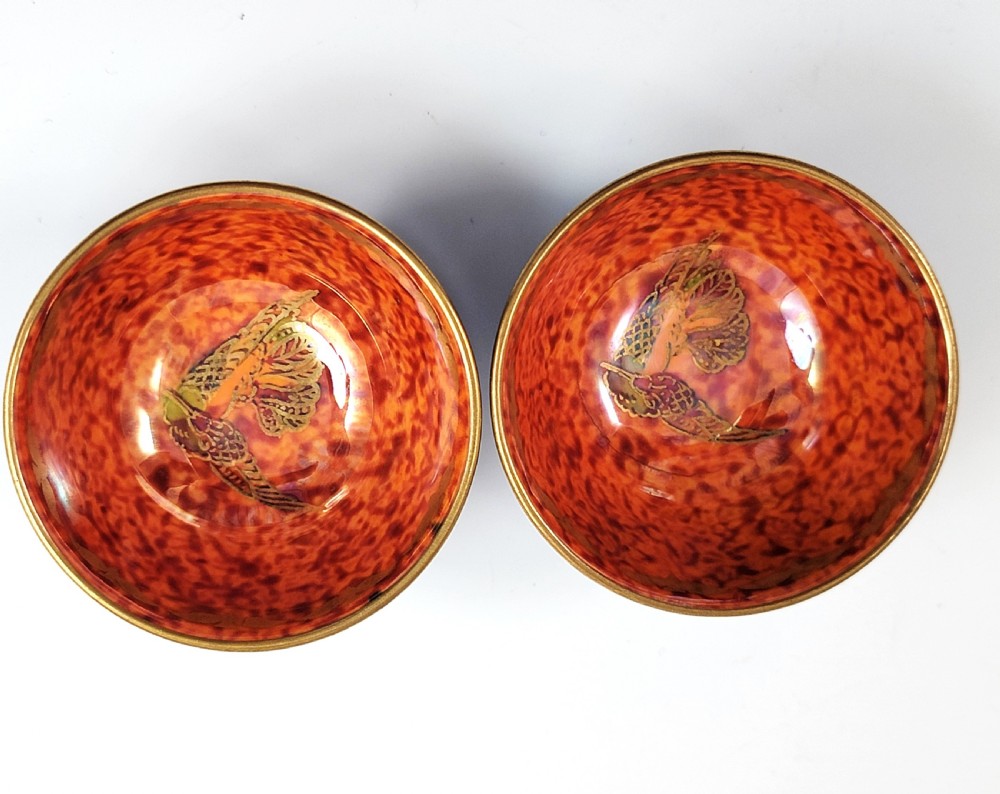 A pair of small Wedgwood lustre porcelain bowls featuring a cobalt blue exterior decorated with gilt birds and a mottled orange interior. View IX