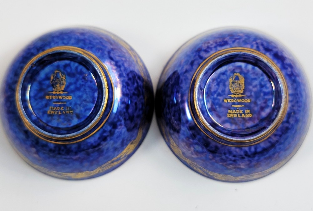 A pair of small Wedgwood lustre porcelain bowls featuring a cobalt blue exterior decorated with gilt birds and a mottled orange interior. View X