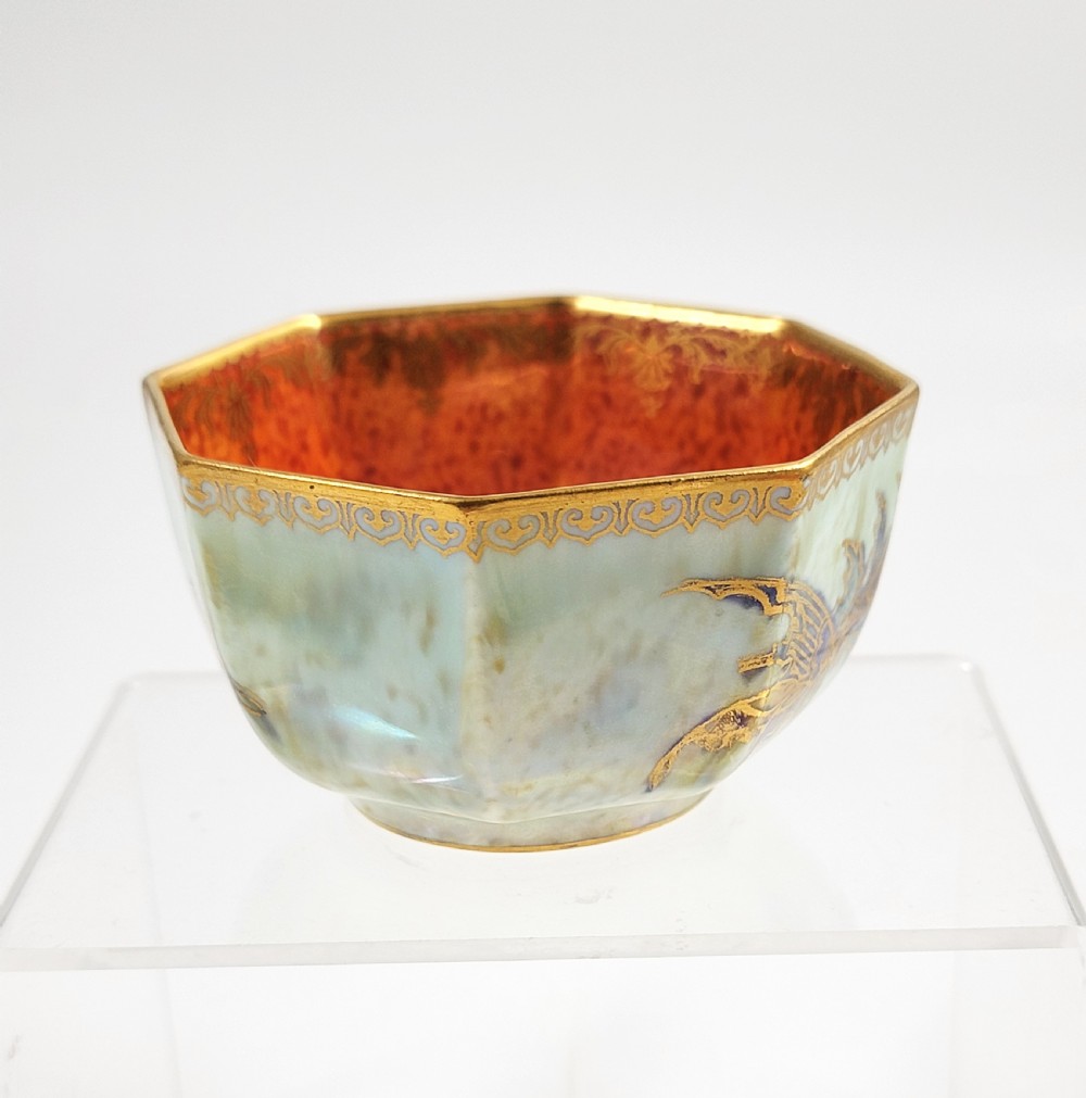 An octagonal ceramic bowl featuring a mottled pale blue and green iridescent exterior with gilt motifs and a bright orange mottled interior with gold borders. View VII