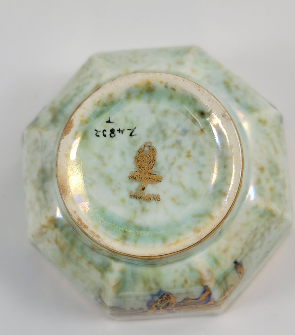 An octagonal ceramic bowl featuring a mottled pale blue and green iridescent exterior with gilt motifs and a bright orange mottled interior with gold borders. View IX