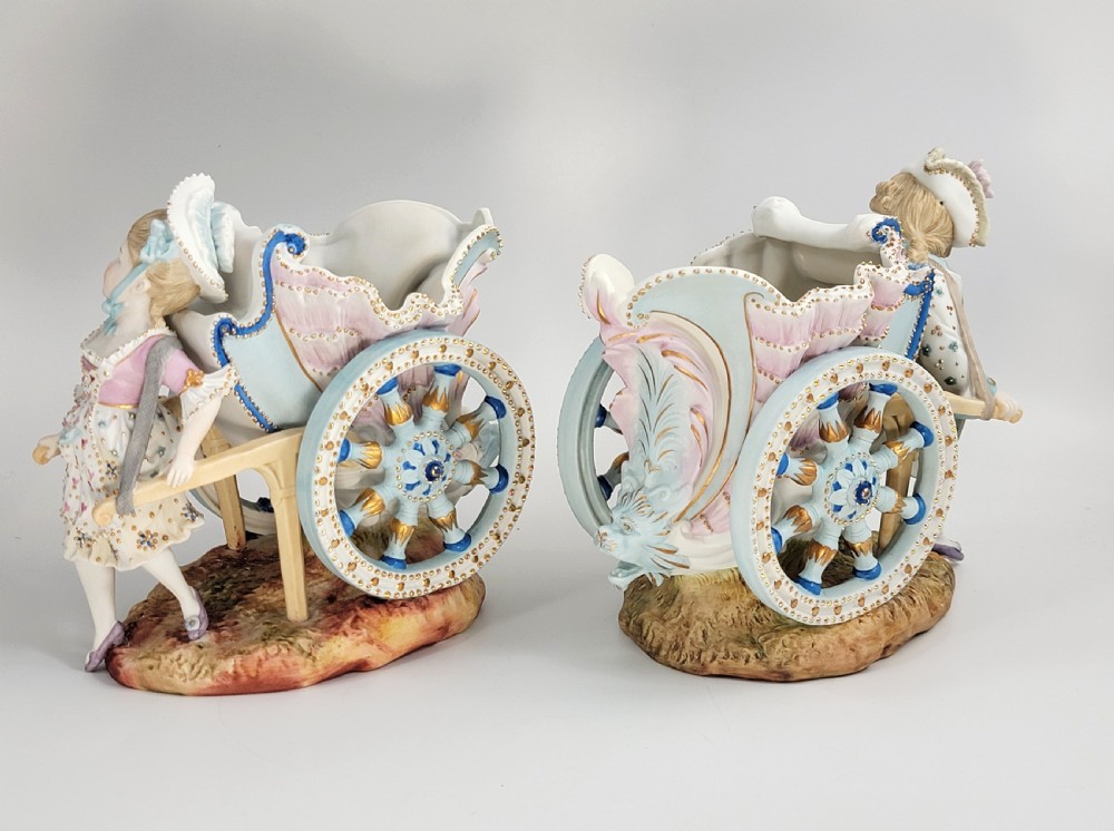 A pair of late 19th-century German hand-painted porcelain figural flower carts featuring a male and female figure in 18th-century attire pulling gilded two-wheeled carriages. View III