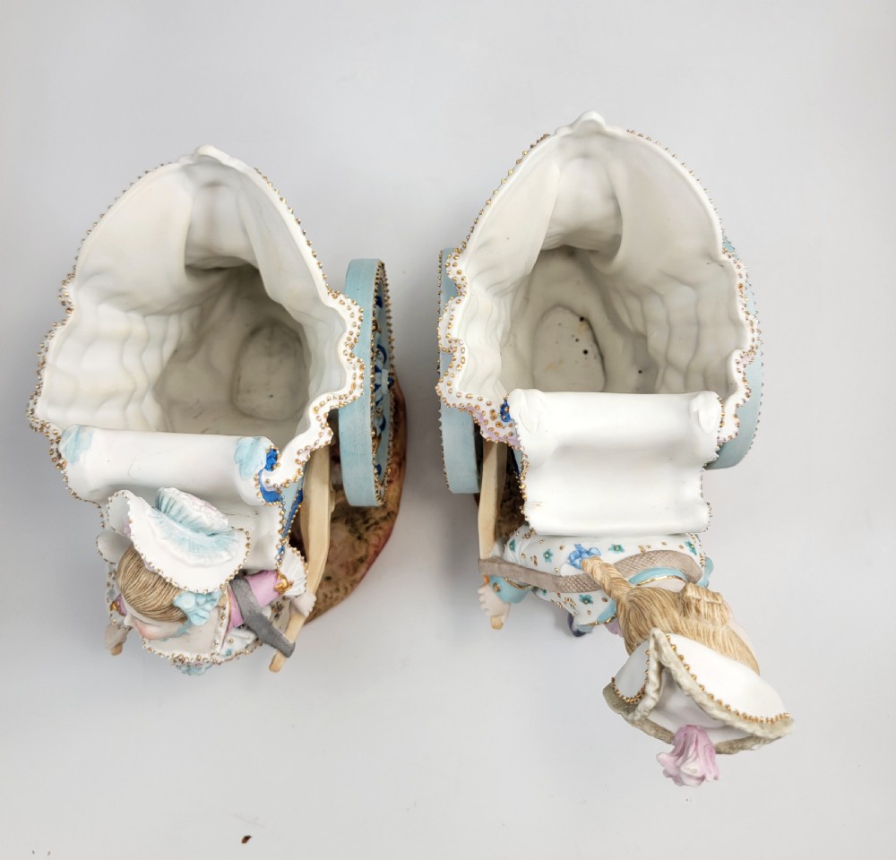 A pair of late 19th-century German hand-painted porcelain figural flower carts featuring a male and female figure in 18th-century attire pulling gilded two-wheeled carriages. View VII