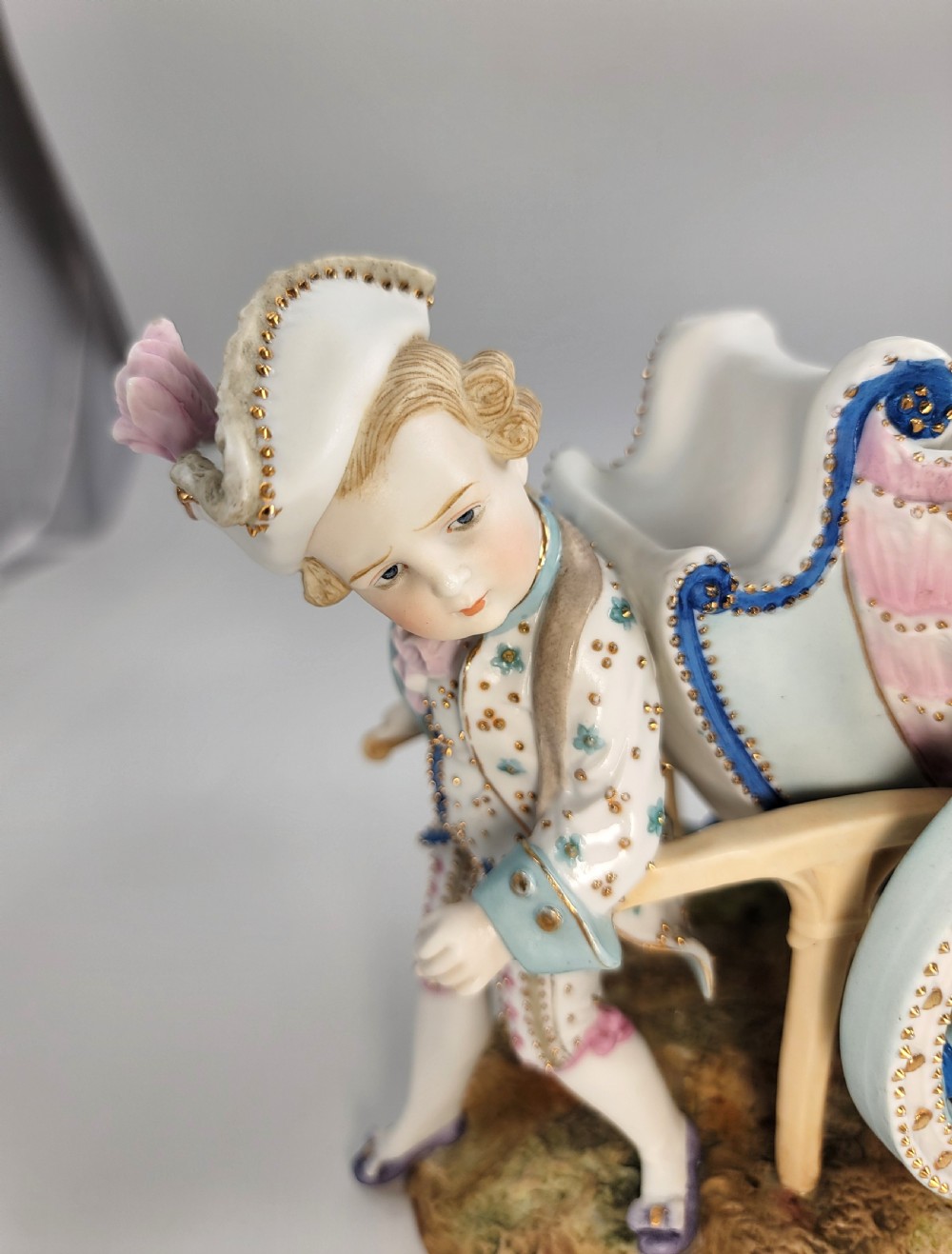 A pair of late 19th-century German hand-painted porcelain figural flower carts featuring a male and female figure in 18th-century attire pulling gilded two-wheeled carriages. View IX