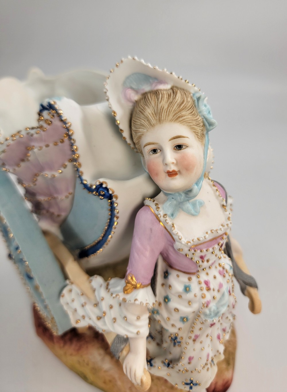 A pair of late 19th-century German hand-painted porcelain figural flower carts featuring a male and female figure in 18th-century attire pulling gilded two-wheeled carriages. View XI