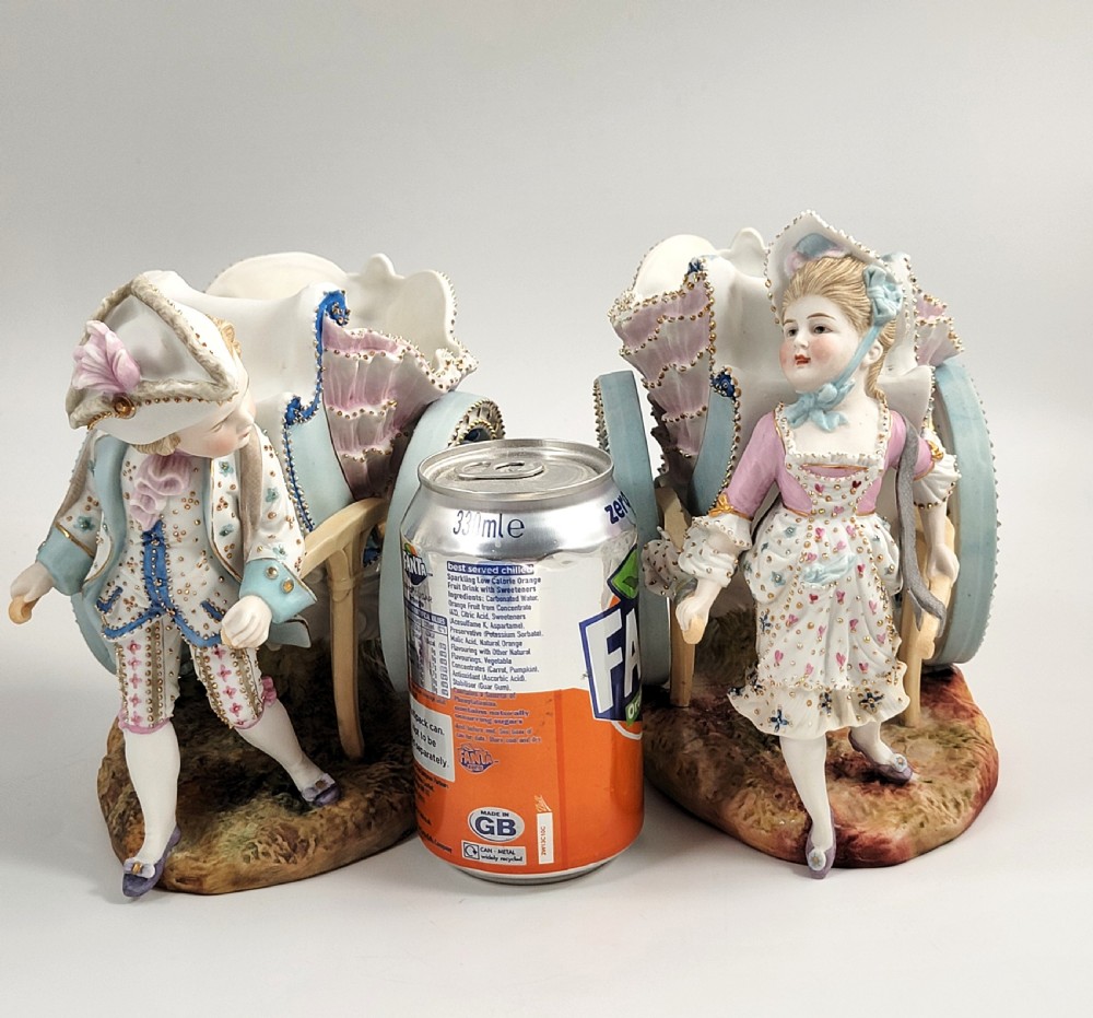 A pair of late 19th-century German hand-painted porcelain figural flower carts featuring a male and female figure in 18th-century attire pulling gilded two-wheeled carriages. View XII