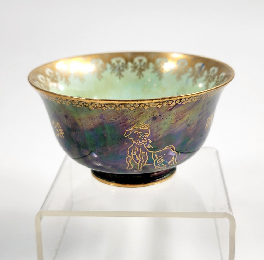 An antique footed porcelain bowl featuring iridescent purple and green glazes decorated with gilt dragons and ornamental borders.