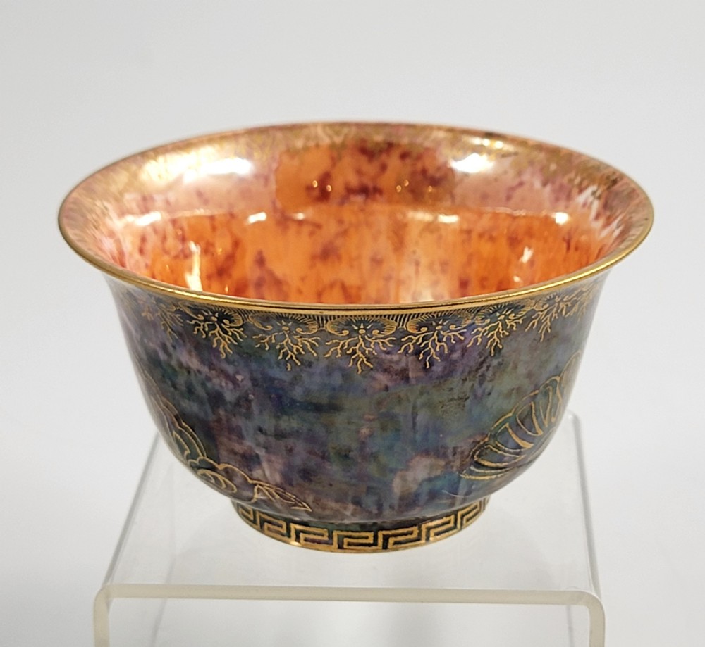 A circular porcelain bowl featuring a mottled iridescent purple exterior decorated with gilt butterfly motifs and a gold-toned orange interior. View V
