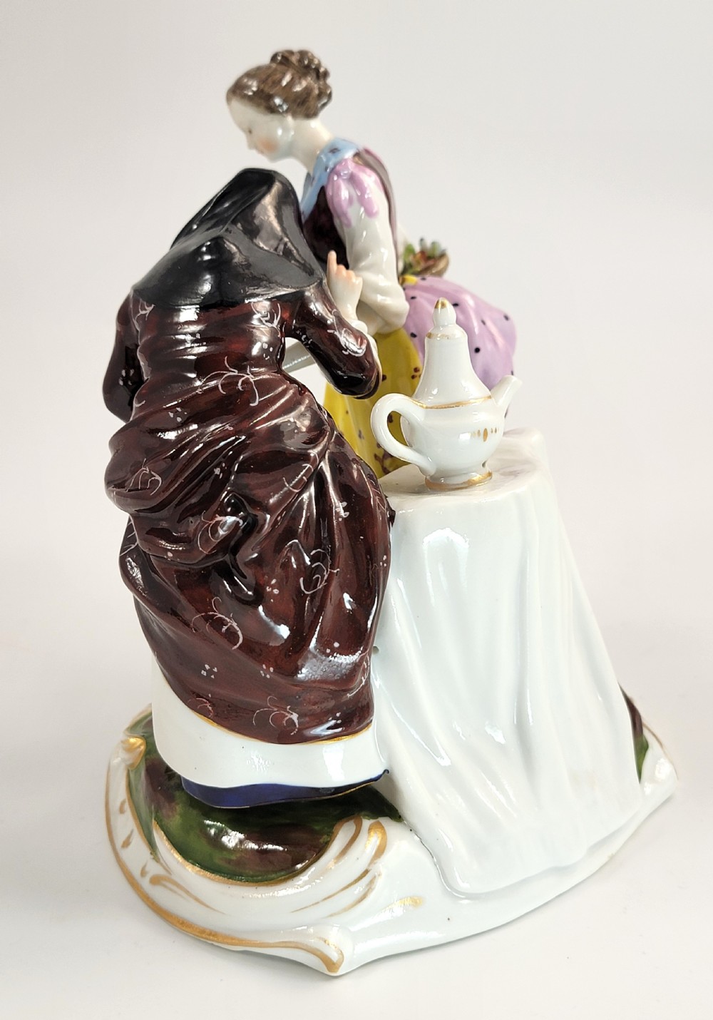 A hand-painted Volkstedt porcelain figural group featuring a fortune teller reading a young womans palm with a small winged cupid figure below. View III