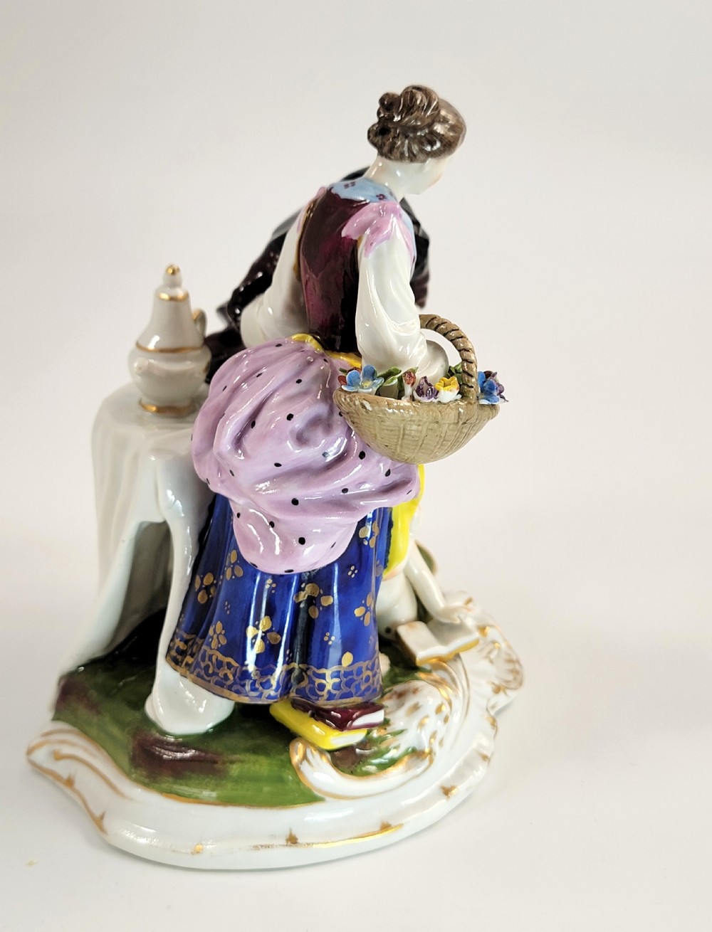 A hand-painted Volkstedt porcelain figural group featuring a fortune teller reading a young womans palm with a small winged cupid figure below. View VII
