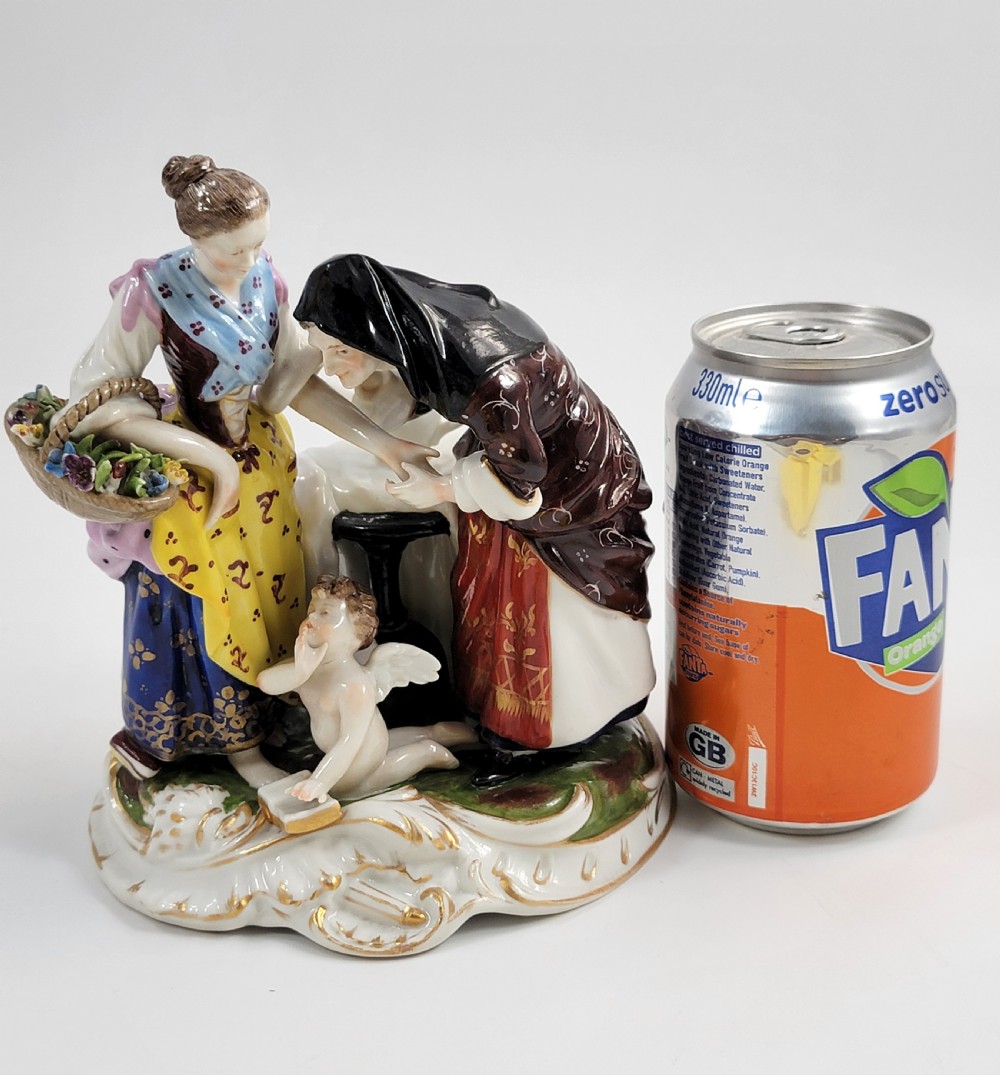 A hand-painted Volkstedt porcelain figural group featuring a fortune teller reading a young womans palm with a small winged cupid figure below. View XII
