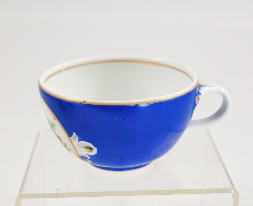 An antique cobalt blue porcelain teacup and matching saucer featuring hand-painted floral medallions and gold rim trim. View IV