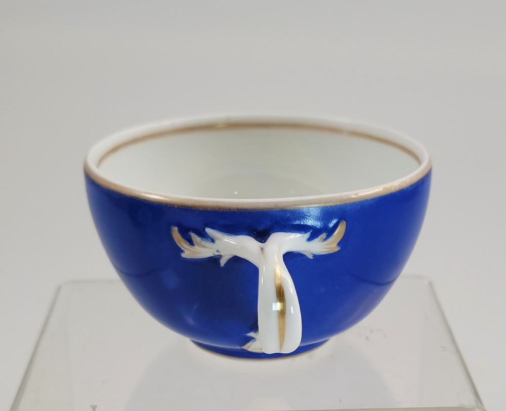 An antique cobalt blue porcelain teacup and matching saucer featuring hand-painted floral medallions and gold rim trim. View V