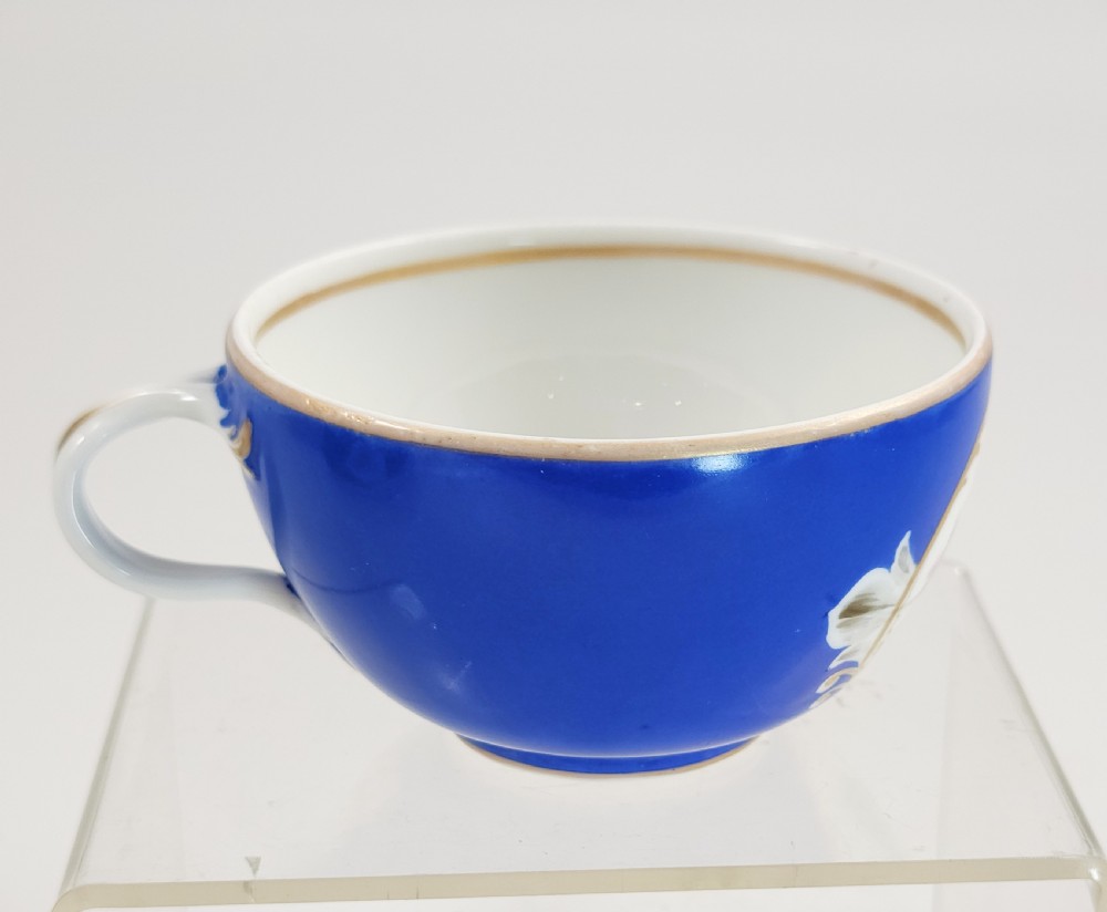 An antique cobalt blue porcelain teacup and matching saucer featuring hand-painted floral medallions and gold rim trim. View VI
