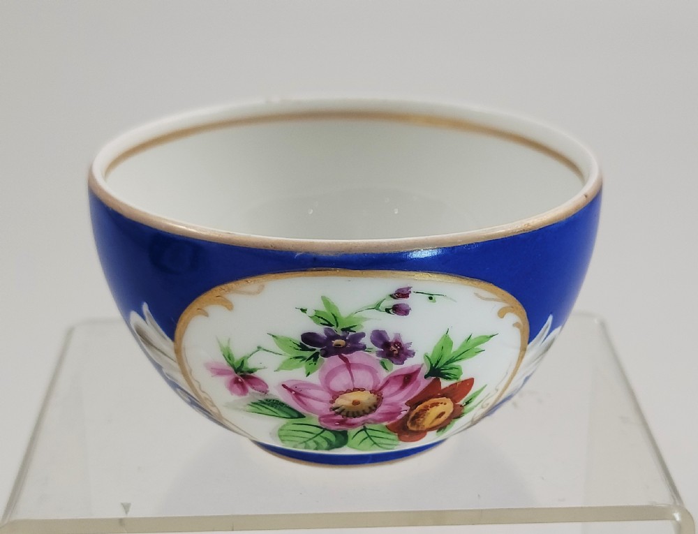 An antique cobalt blue porcelain teacup and matching saucer featuring hand-painted floral medallions and gold rim trim. View VII