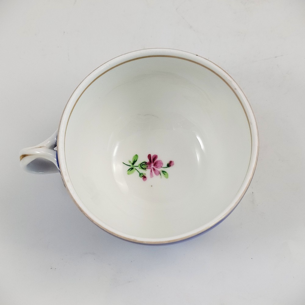 An antique cobalt blue porcelain teacup and matching saucer featuring hand-painted floral medallions and gold rim trim. View VIII