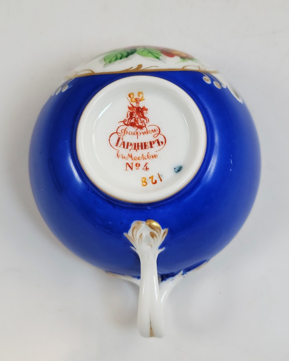 An antique cobalt blue porcelain teacup and matching saucer featuring hand-painted floral medallions and gold rim trim. View IX