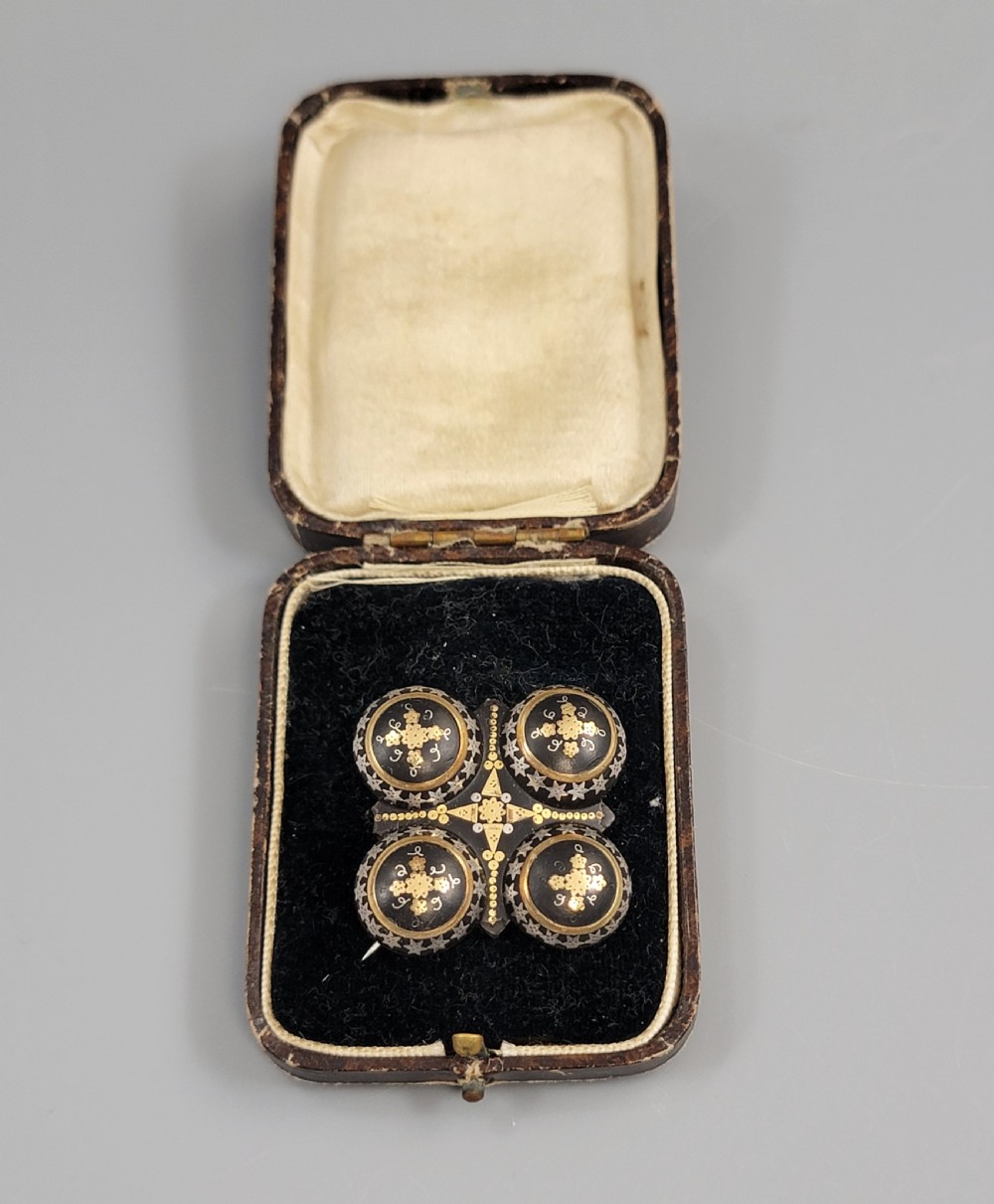 A Victorian quatrefoil brooch crafted from dark tortoiseshell with gold and silver pique work inlay set inside a fitted plush-lined box.