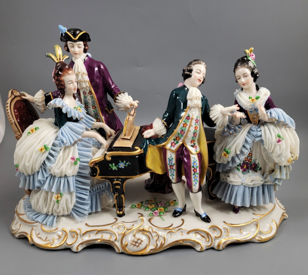 A German porcelain figural group depicting four 18th-century courtly figures around a grand piano with detailed porcelain lace dresses on a black wooden base. View III