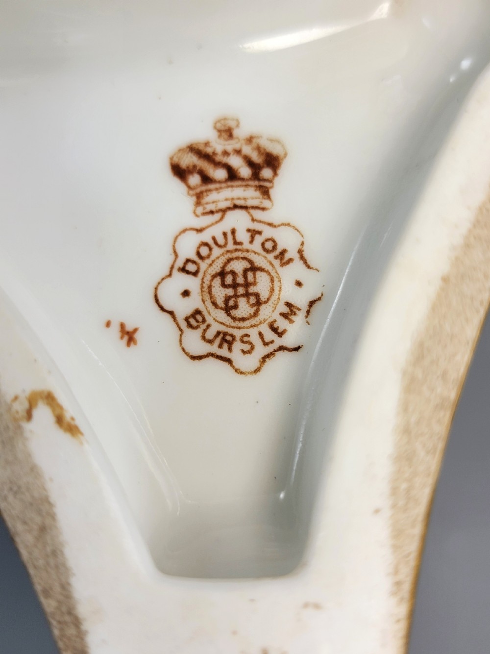 A pair of late Victorian Doulton Burslem porcelain beaker-form vases featuring hand-painted floral motifs and interior gilding, supported by three sculpted dolphin pedestals resting on moulded triangular gold bases. View VIII