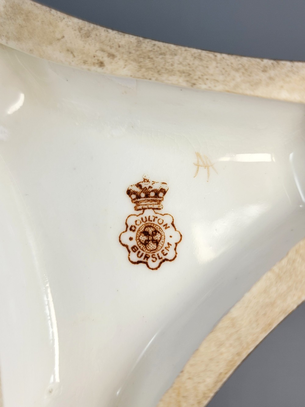 A pair of late Victorian Doulton Burslem porcelain beaker-form vases featuring hand-painted floral motifs and interior gilding, supported by three sculpted dolphin pedestals resting on moulded triangular gold bases. View IX