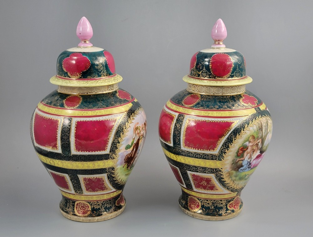 A pair of nineteenth-century Royal Vienna style porcelain covered urns featuring hand-painted classical figures inside oval gilt reserves, set against teal, pink, and yellow enamelled grounds. View VI