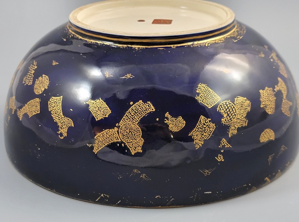 A circular Japanese Satsuma earthenware bowl featuring a central scene of samurai warriors in gold and polychrome enamels surrounded by a dark cobalt blue rim decorated with intricate gold scrollwork. View XI