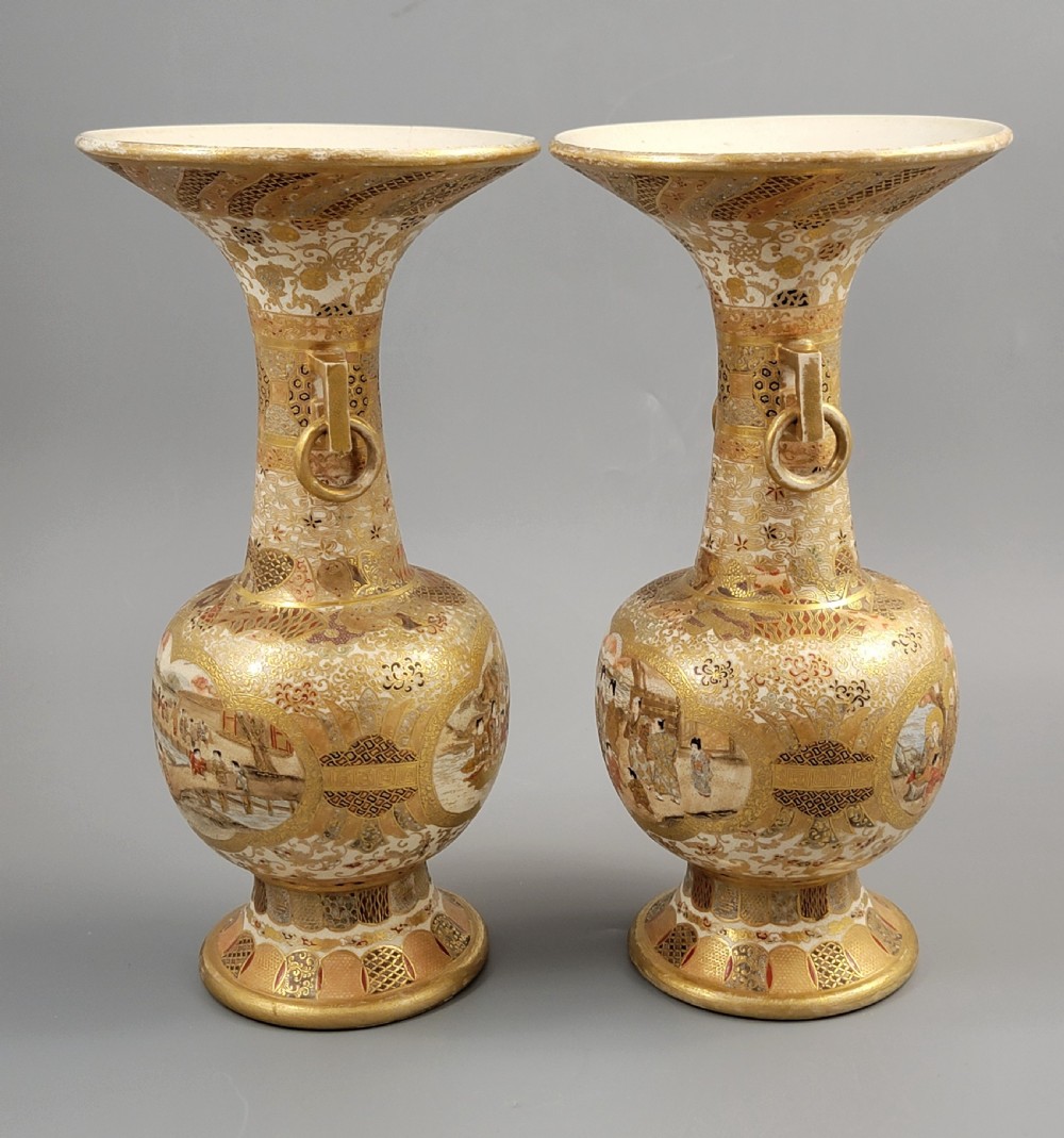 A pair of Japanese Satsuma earthenware vases featuring flared rims, fixed ring handles, and detailed hand-painted figural panels with extensive gold gilding. View VII
