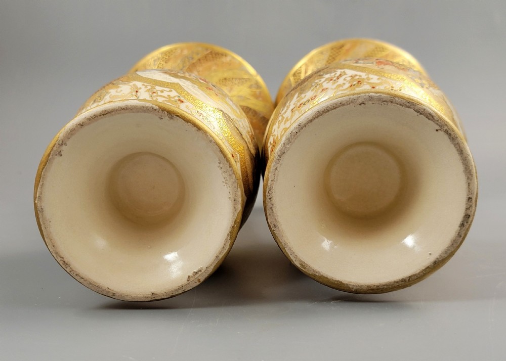 A pair of Japanese Satsuma earthenware vases featuring flared rims, fixed ring handles, and detailed hand-painted figural panels with extensive gold gilding. View IX