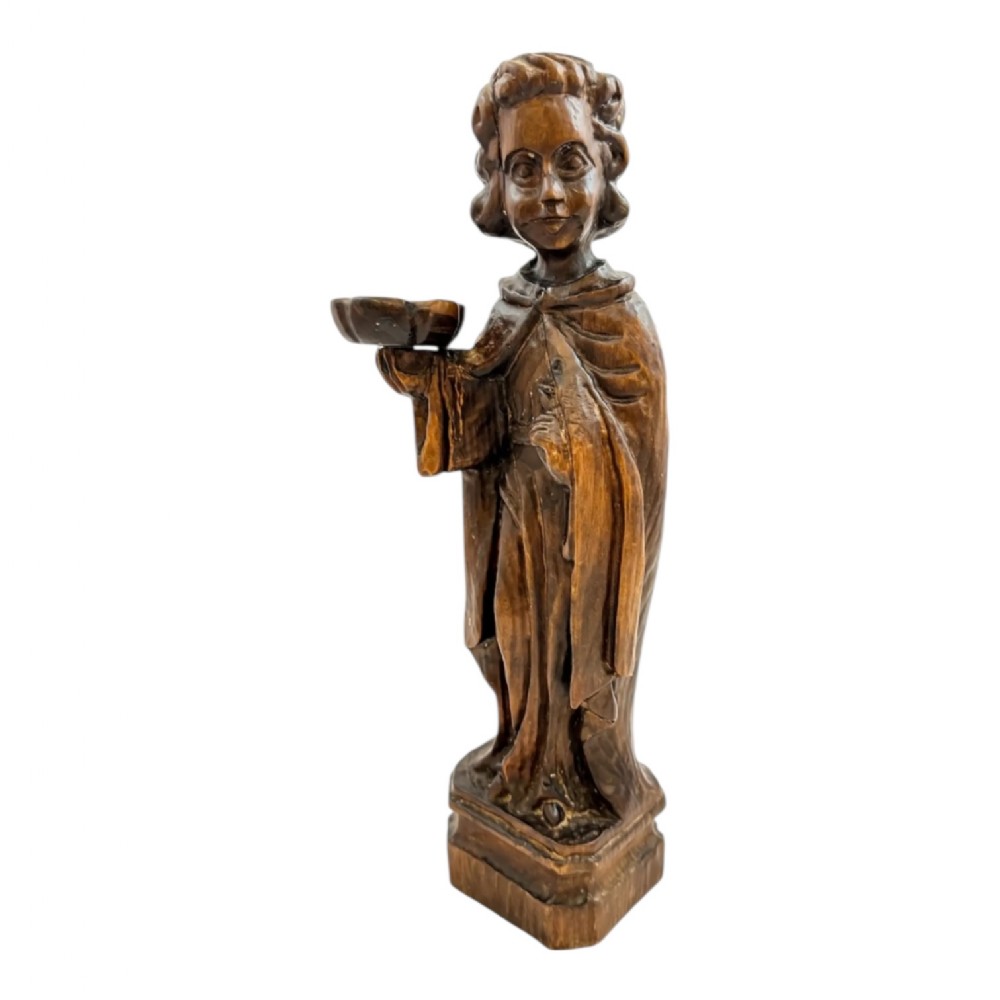 An 18th-century Continental carved wooden figure of an acolyte in draped robes holding a small dish, mounted on a square plinth.
