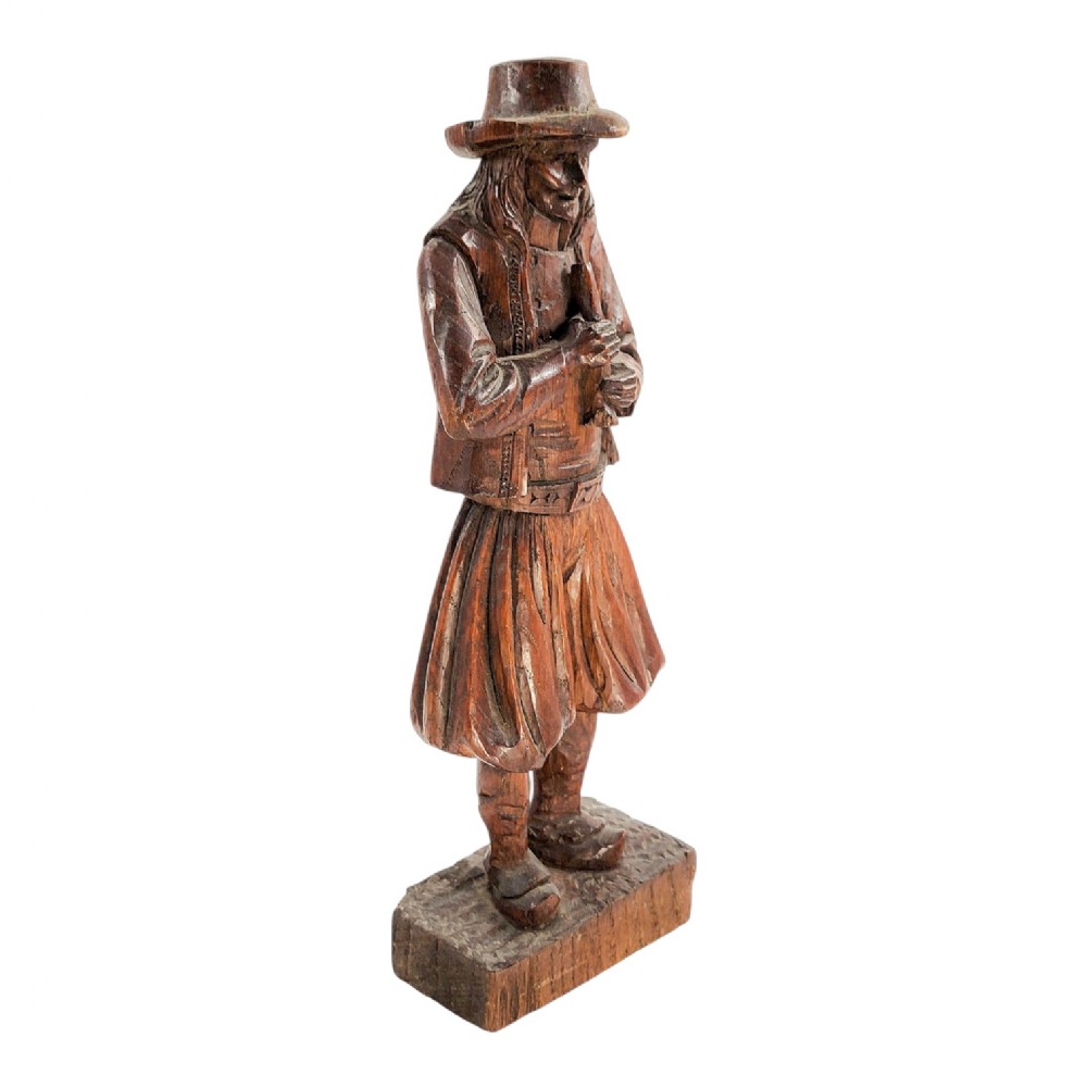 A nineteenth-century hand-carved oak figure depicting the Pied Piper standing on a rectangular base while playing a musical pipe.