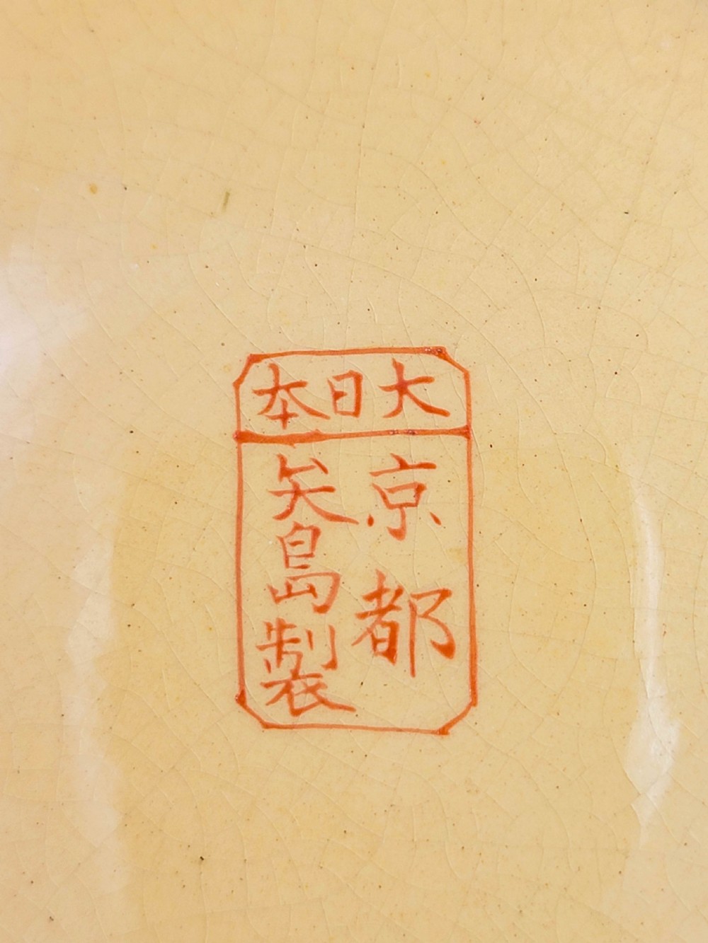 A circular Japanese Satsuma earthenware plate featuring a fine crackle glaze, detailed polychrome figures in traditional dress near a landscape building, and a gilded geometric border. View XI