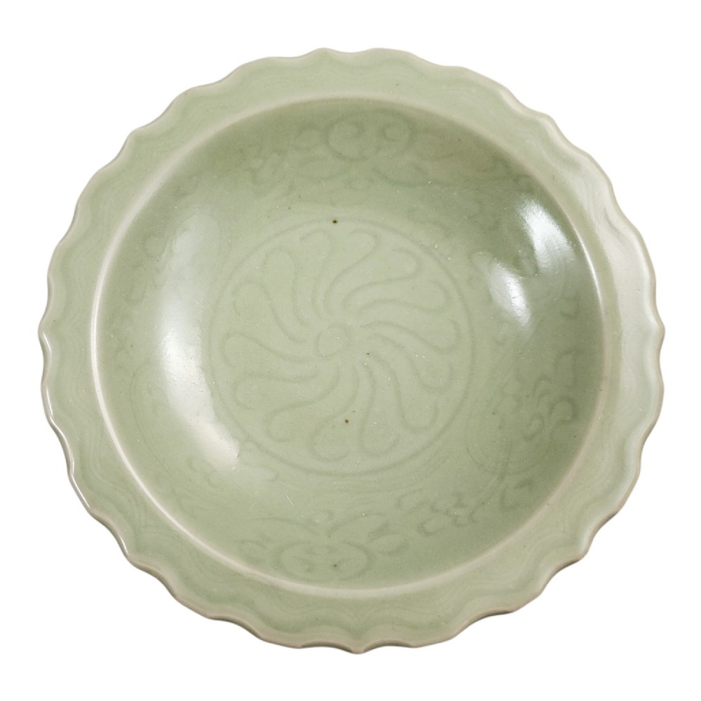 A light celadon green ceramic dish with a scalloped foliate rim and incised floral motifs carved into the interior surface.