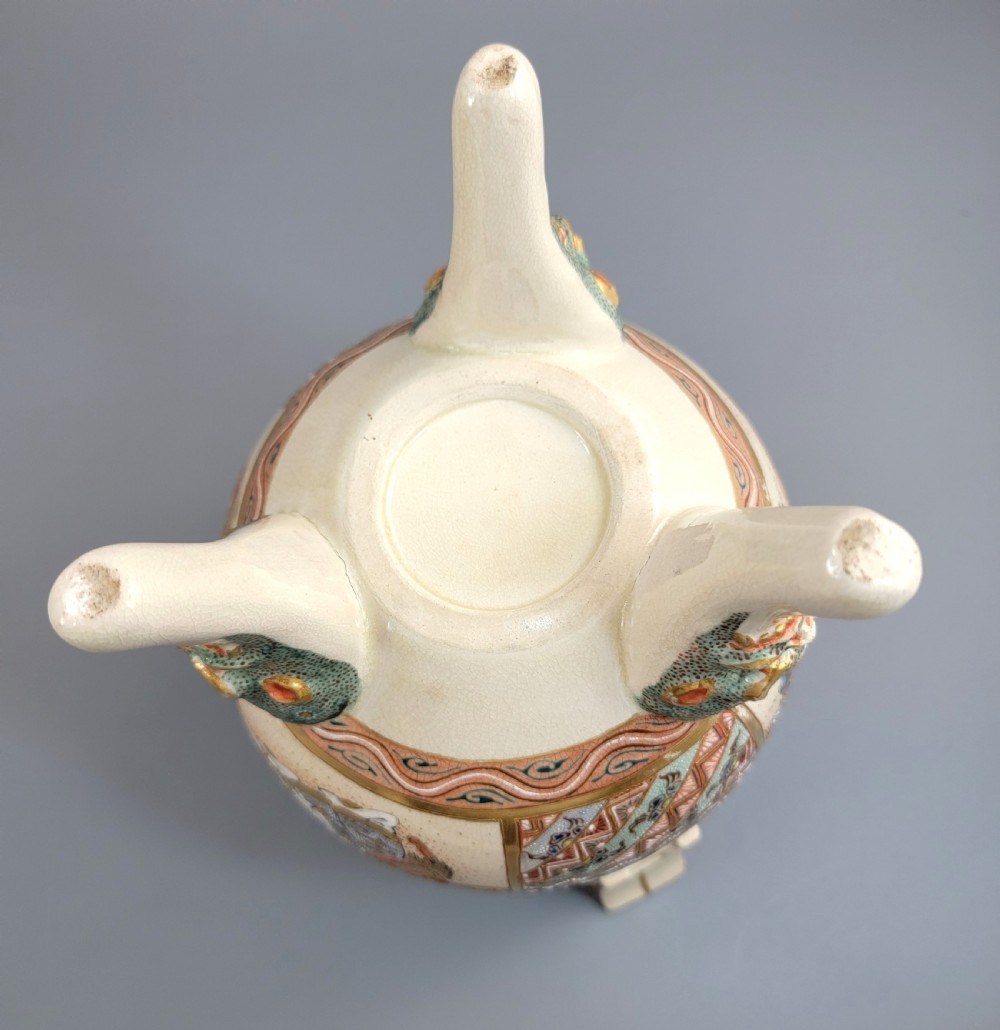 A cream-coloured Japanese Satsuma earthenware incense burner featuring a lid with a shishi lion finial, upright handles, tripod feet, and detailed polychrome paintings of samurai warriors with gold accents. View XV