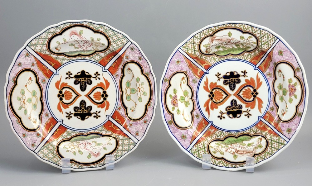 A pair of circular late 18th-century Derby porcelain plates featuring scalloped rims and hand-painted polychrome Kylin pattern designs in orange, cobalt blue, pink, and green.