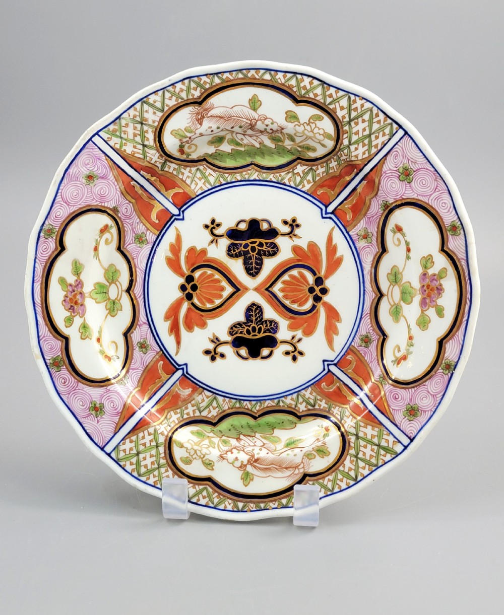 A pair of circular late 18th-century Derby porcelain plates featuring scalloped rims and hand-painted polychrome Kylin pattern designs in orange, cobalt blue, pink, and green. View II
